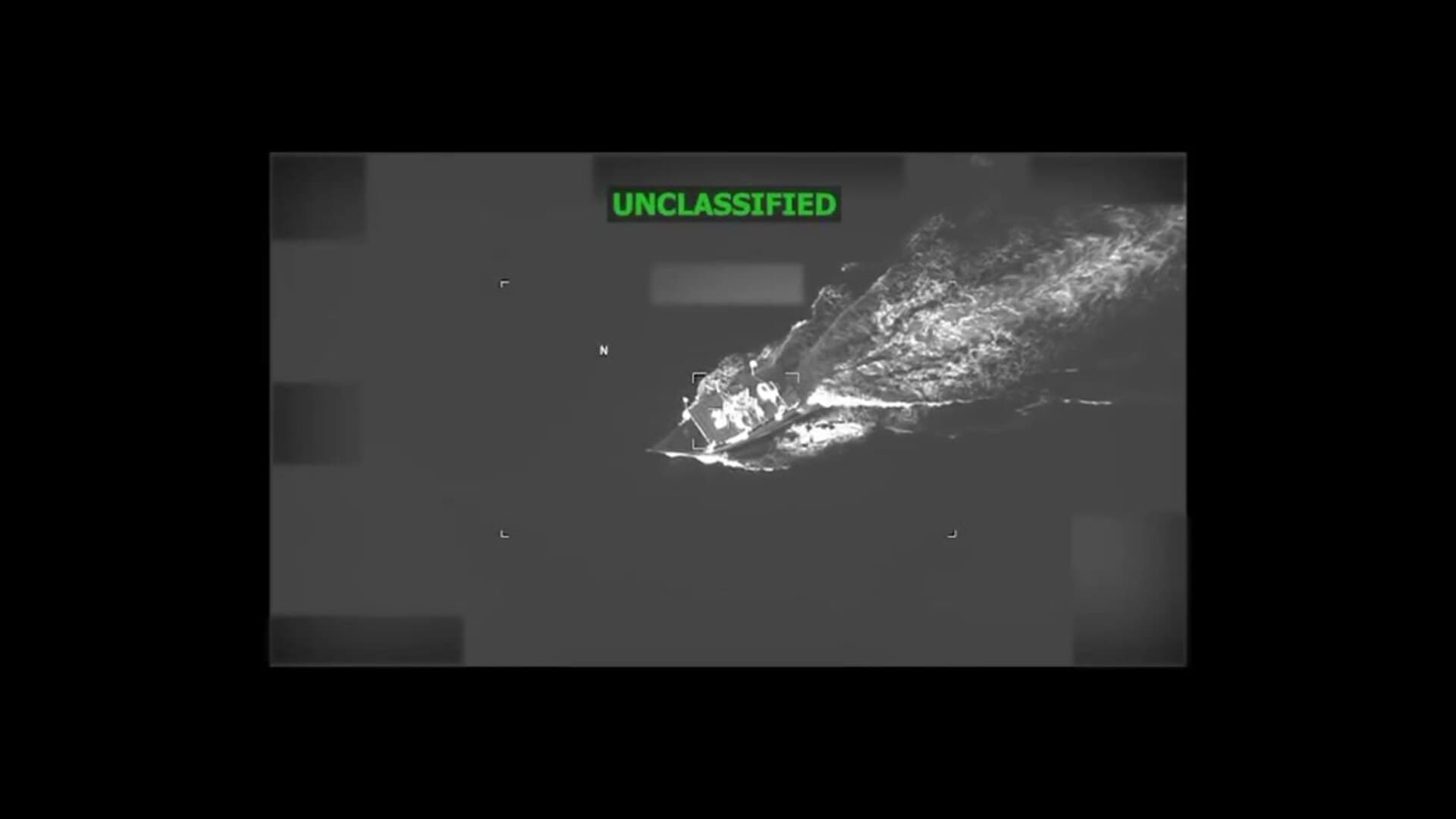 Monochrome aerial footage shows a boat moving through the Caribbean before a U.S. military strike.