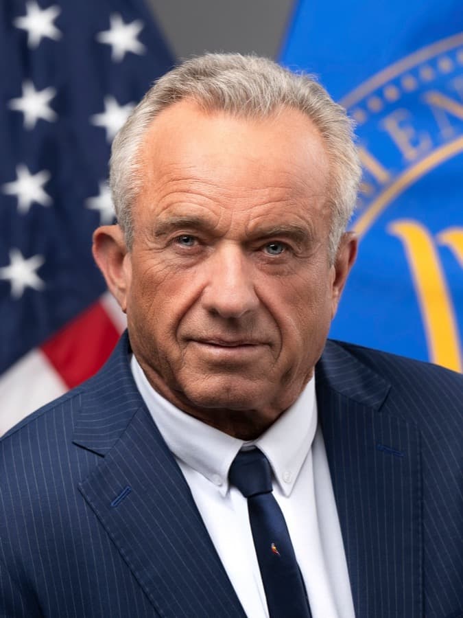 Official portrait of Robert F. Kennedy Jr. in a dark suit and tie in front of a U.S. flag.