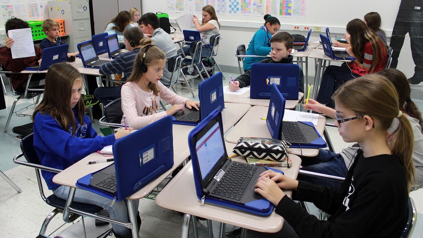 Middle-school students use Chromebooks at classroom desks.