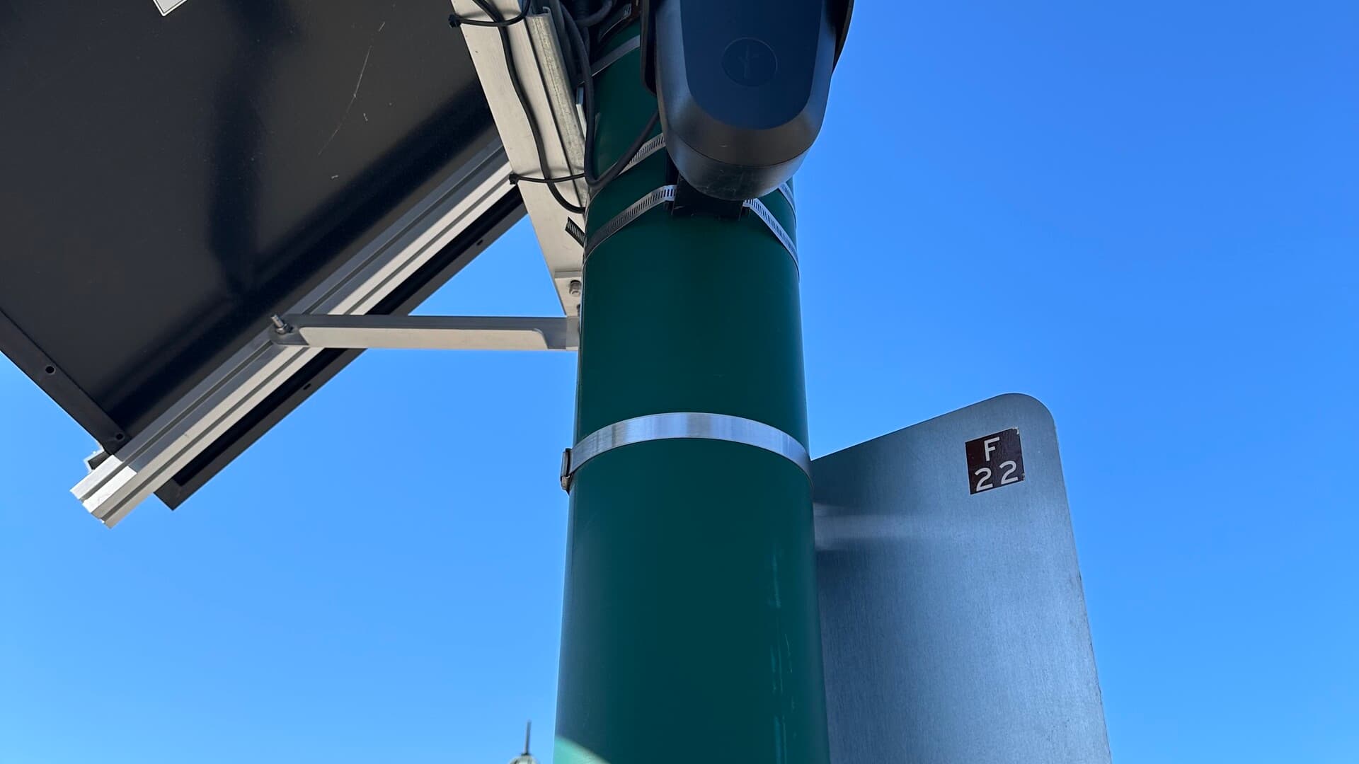 A close view of a green Flock Safety automated license-plate reader mounted beside a street.