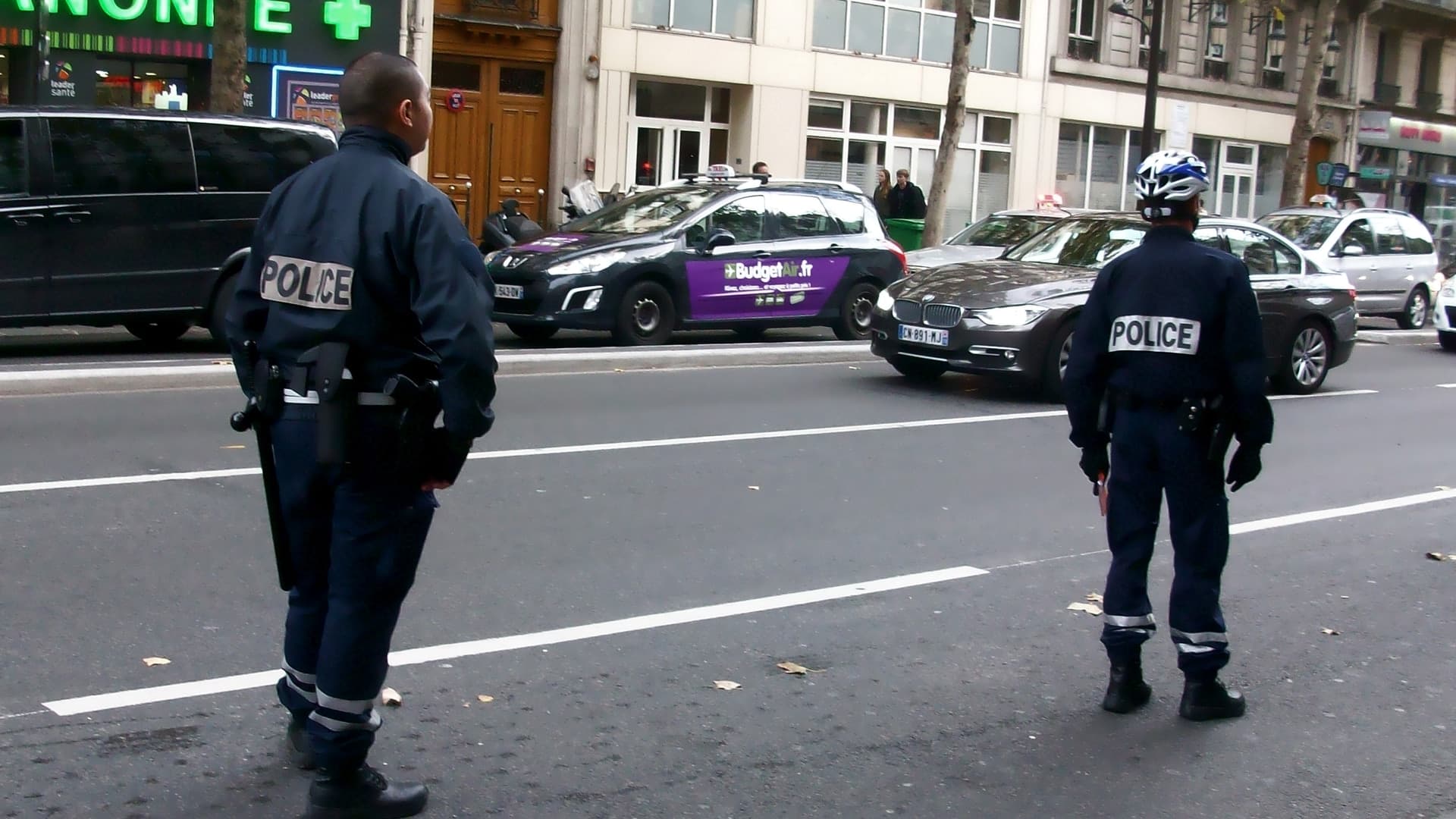 Two French National Police officers standing beside a Paris street.