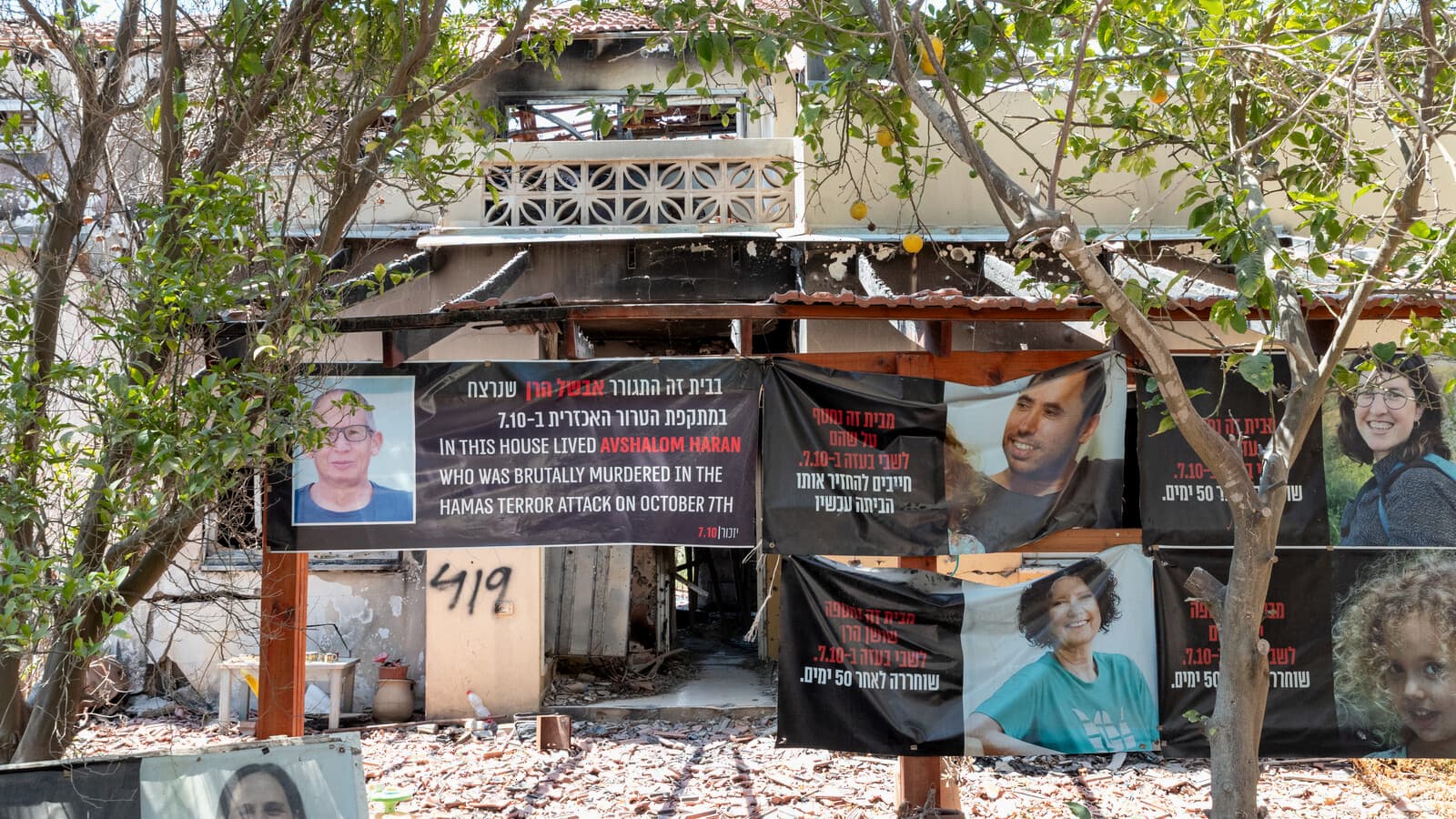 A damaged house at Kibbutz Be'eri hung with memorial banners for residents killed on October 7, 2023.