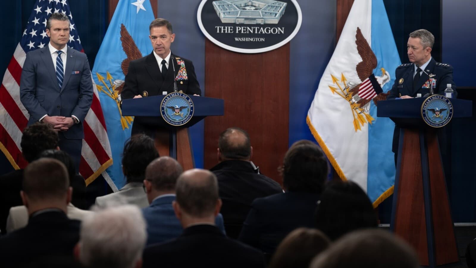 Pete Hegseth stands beside Gen. Dan Caine and Adm. Brad Cooper during a Pentagon press briefing.