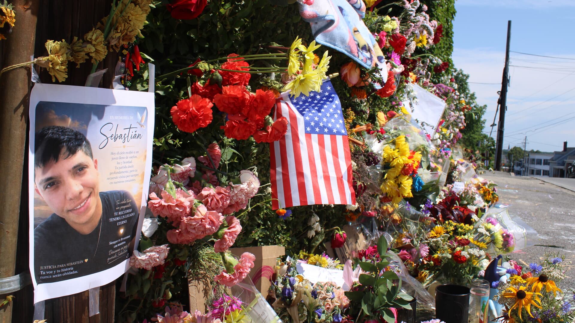 Flowers, signs, photographs, and an American flag at the memorial for Johan Sebastián Durán Guerrero in Biddeford, Maine.