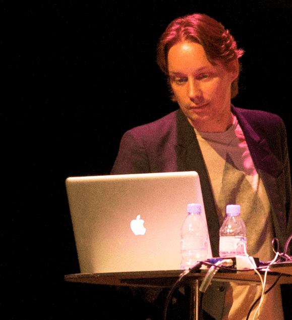 Joris de Man standing behind a laptop on a stage