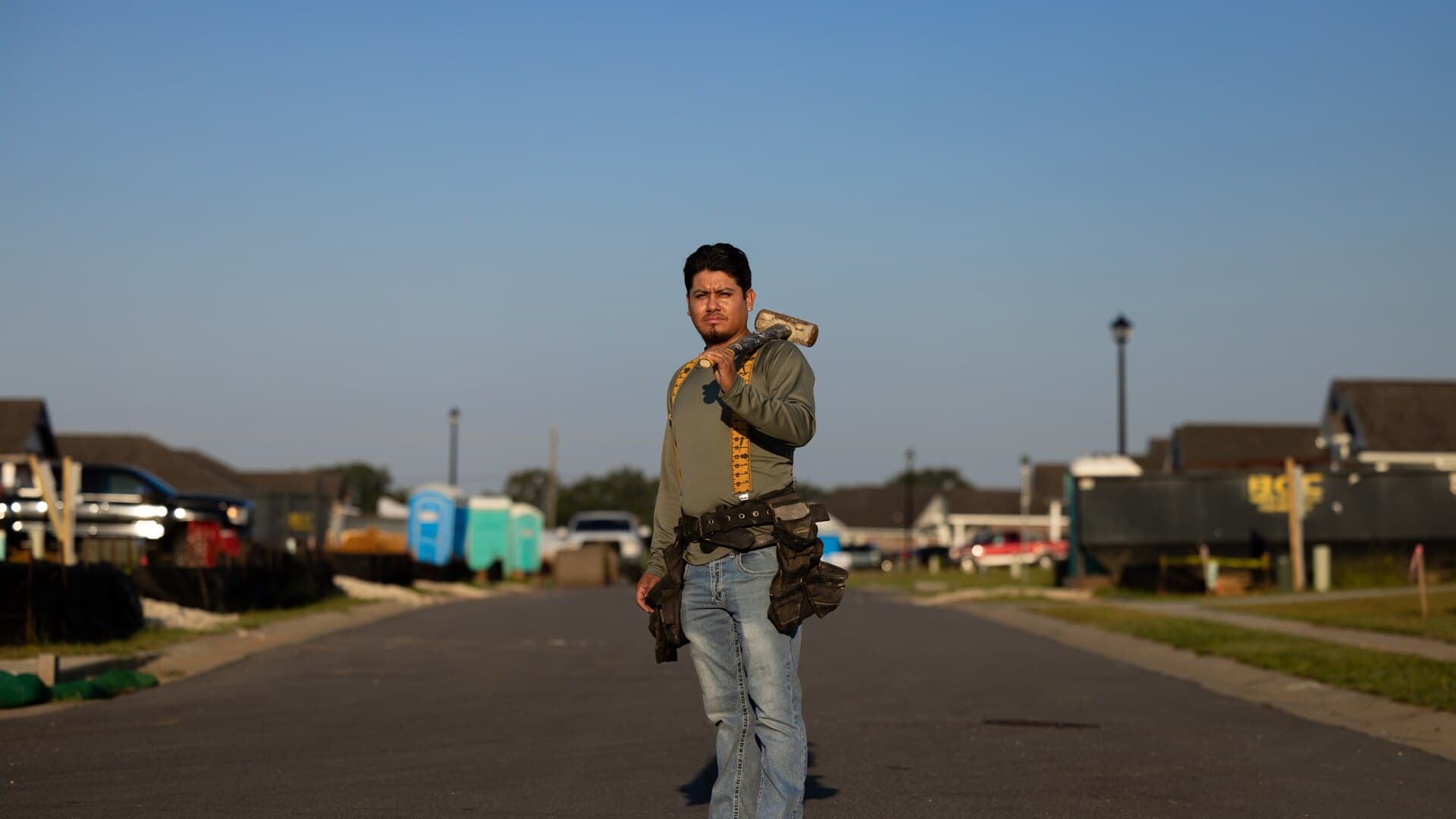 Leo Garcia Venegas stands on a residential street in Baldwin County, Alabama, wearing construction gear and holding a sledgehammer.