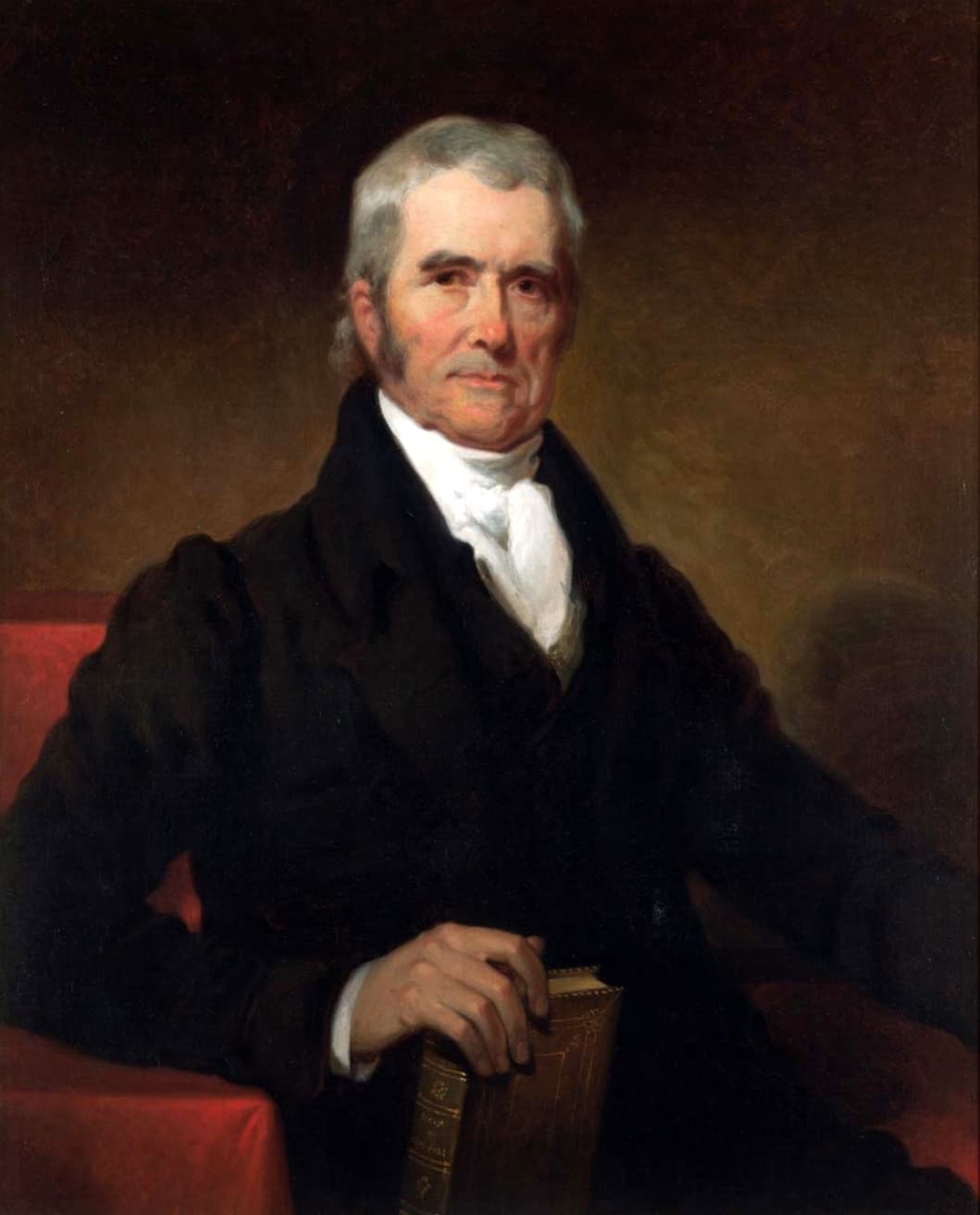 Oil portrait of Chief Justice John Marshall as an older man with gray hair, in a black coat and white cravat, seated beside a red-draped table with his hand resting on a book.
