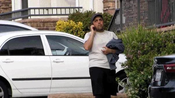 Man holding a phone near parked vehicles