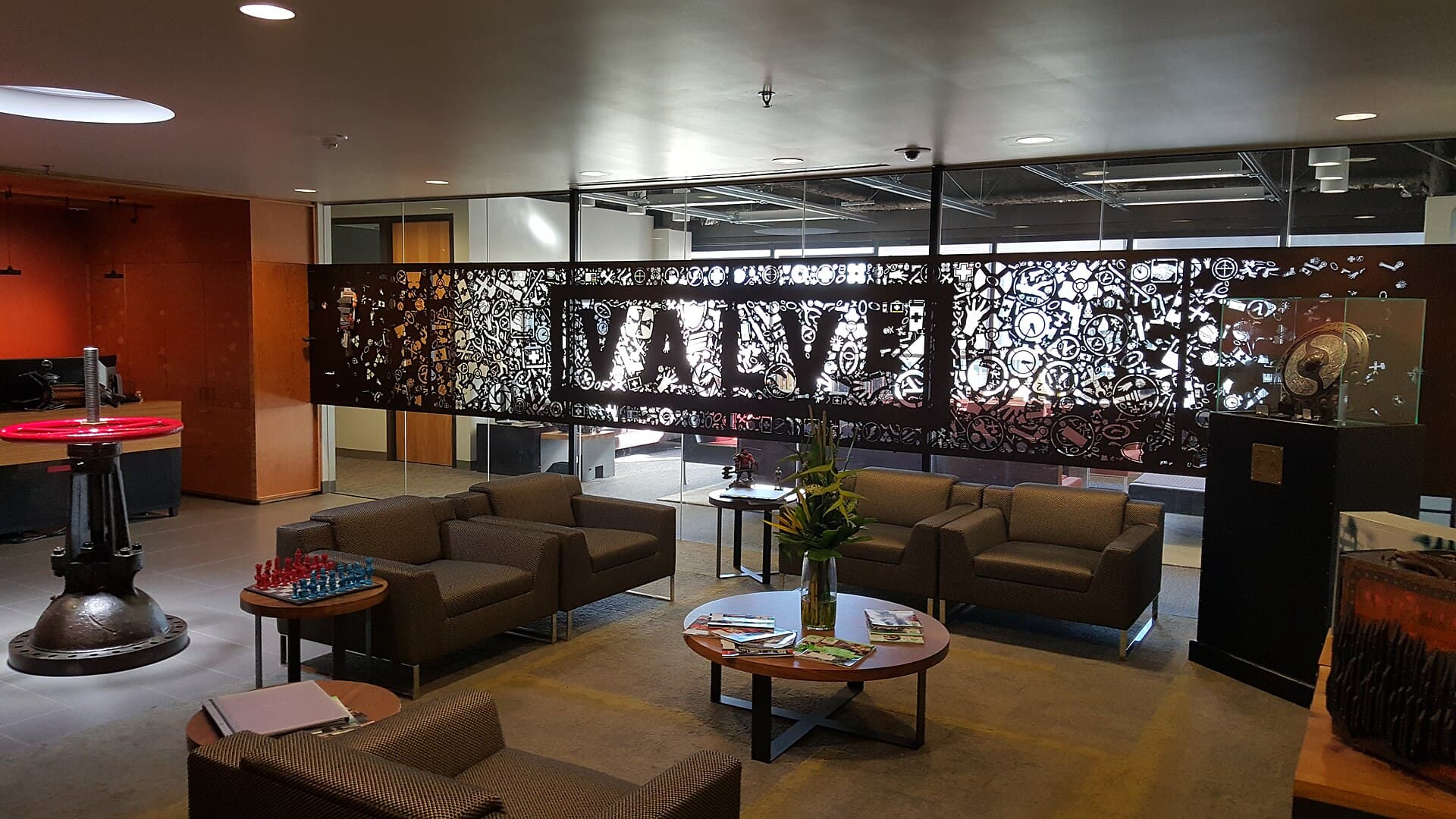 Lobby of Valve's offices with sofas around a low table and a large decorative metal screen spelling VALVE