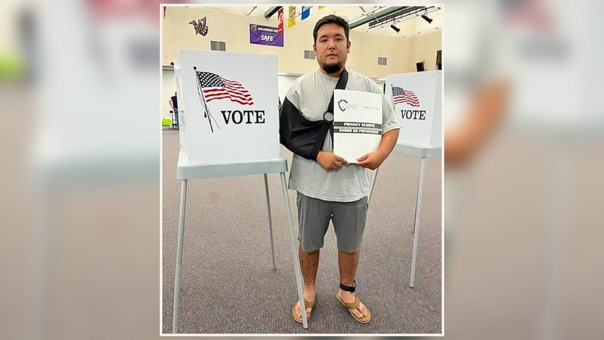 Carlos Jimenez standing at a polling place with his arm in a sling after being shot by an immigration agent.