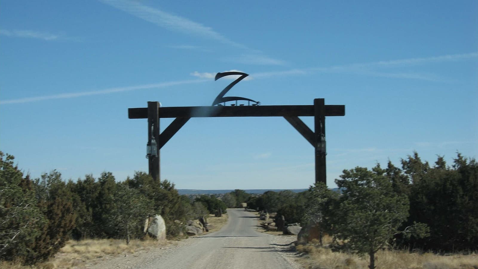 A dirt road passes beneath the wooden Zorro Ranch entrance gate in New Mexico.