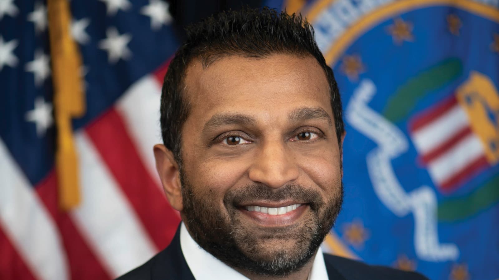 Kash Patel in his official FBI portrait, with the U.S. and FBI flags behind him.