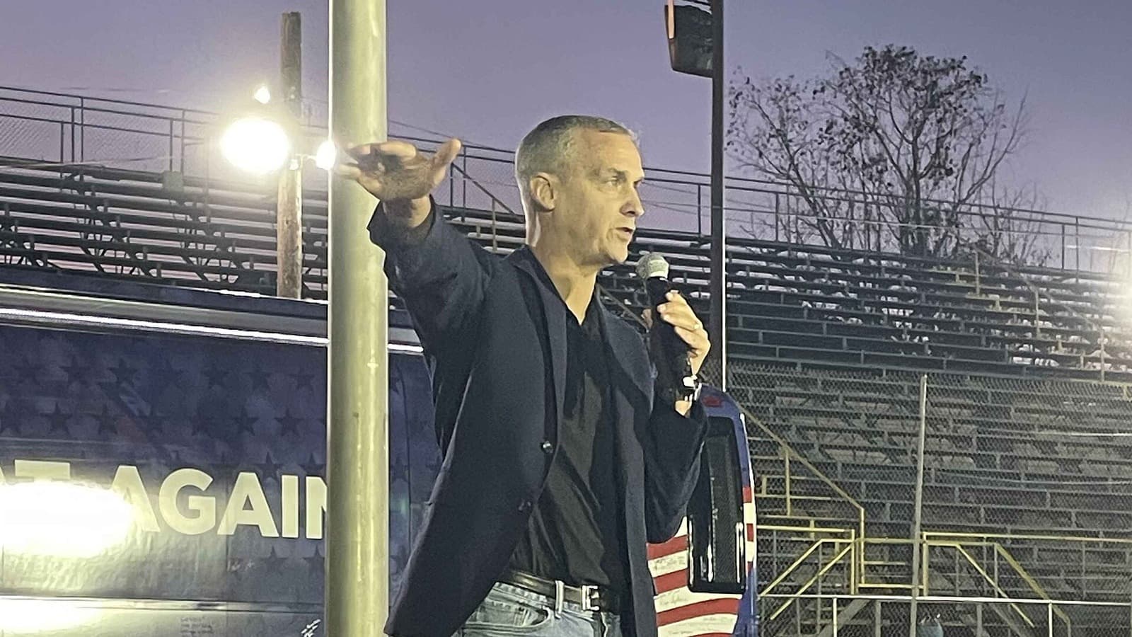 Corey Lewandowski speaks into a microphone at an outdoor rally.