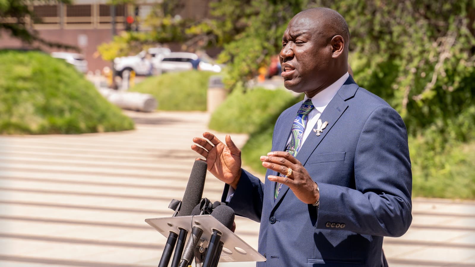 Ben Crump speaks to reporters beside microphones outside a federal courthouse.