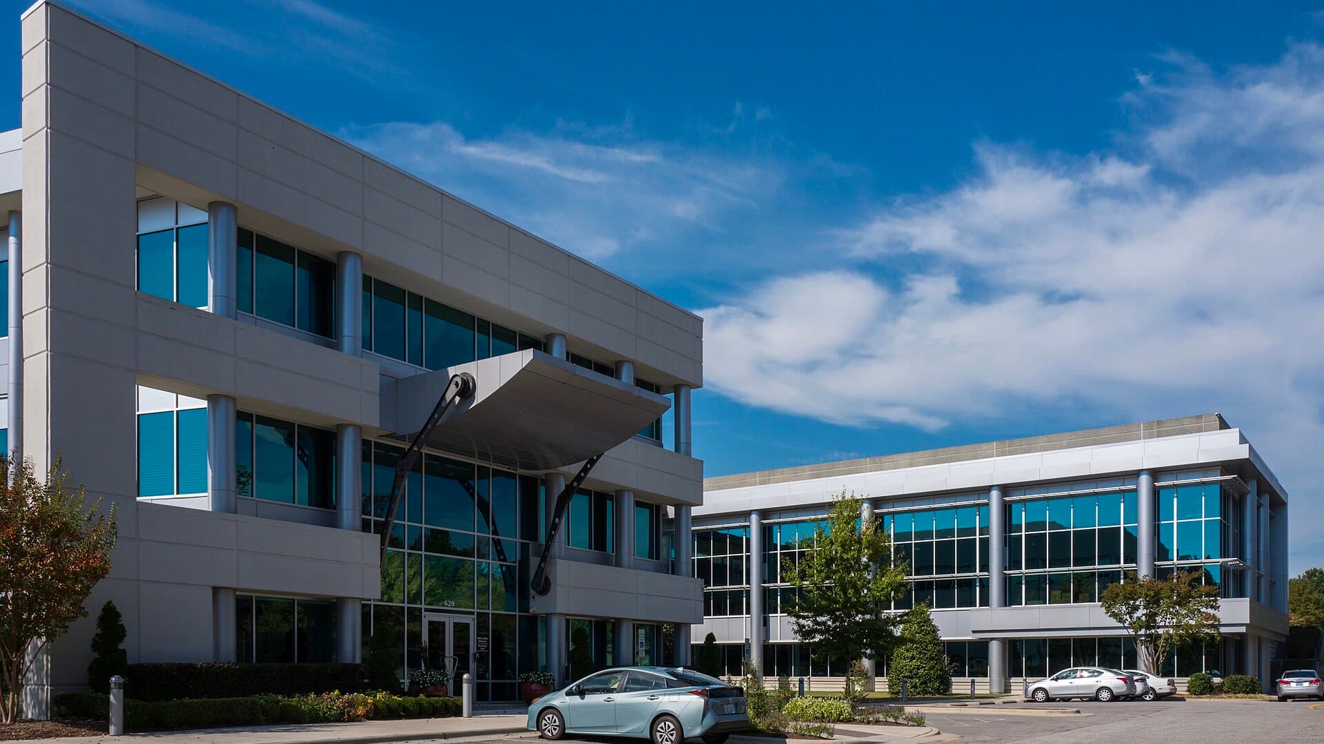 Two modern office buildings with glass facades and a curved entrance canopy at Epic Games' headquarters campus under a blue sky